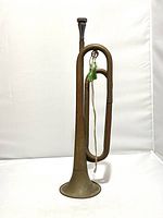 Full view of the vintage brass bugle standing upright showing entire instrument including tubing and bell
