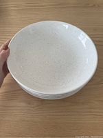 Stack of four speckled white pasta bowls shown from above, displaying the interior and speckled design.