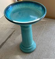 Blue ceramic bird bath with a wide shallow bowl and sturdy pedestal.