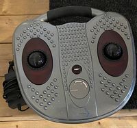 Top-down view of the gray foot massager showing control panel, textured footpads, and power cord.