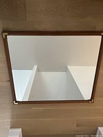 Top-down view of rectangular solid mahogany framed mirror reflecting ceiling and walls.