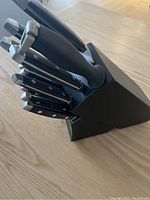 Black wooden kitchen knife block holding 10 knives with black handles
