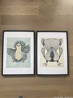 Two framed prints side by side on wood floor