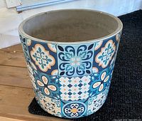 Ceramic pot with colorful tile-like decorative pattern shown from front angle.