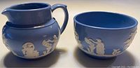 Blue jasperware creamer and sugar bowl set with white classical relief decorations on blue body
