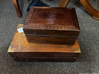 Top and side view of smaller geometric inlaid antique wooden box stacked over larger plain wooden box with brass hardware