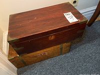Photo showing two stacked antique wooden writing boxes with dark wood finish and brass corner reinforcements.