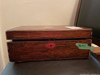 Side view of one antique wooden writing box showing wood grain and red keyhole escutcheon.