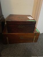 Photo showing the two wooden antique writing boxes stacked, highlighting wood grain and brass hardware.