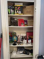 Four shelves with various boxed electronics, books, globe, lights and stationery items.
