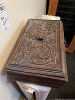 Carved wooden box viewed from above showing detailed carved floral and vine pattern on the lid.