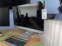 HP monitor and Hipstreet wireless keyboard placed on wooden table with radiator in background.