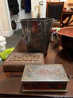 Photo showing tarnished silverplated ice bucket with handcarved wooden box and enamelled brass box on wooden table