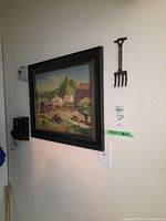 Photo of framed oil painting on a wall showing a rural landscape with trees, barn, and dirt path.