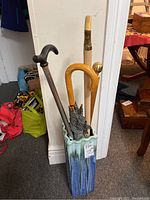 Photo of umbrella stand holding umbrella and three canes, showing full lot