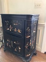 Full side and front angled view of the black lacquer bar cabinet showing painted Asian scenes and cabinet structure with visible chips and scratches in lacquer.