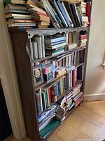 Full view of the wooden bookcase filled with books and other items, showing structure and overall condition.