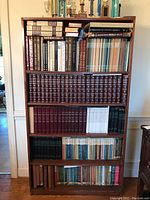 Full bookshelf filled with multiple large encyclopedia volumes and assorted books.