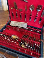 Close angle showing the variety of bronze cutlery and serving utensils with their decorative bronze handles laid neatly in the case.