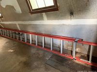 Full-length view of the ladder stored horizontally in a garage space under a window, showing side rails and rungs