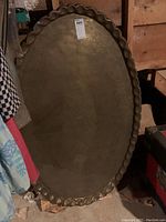 Full view of the large heavy oval metal tray with scalloped edge and visible patina.