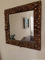 Full view of the square mirror showing the entire metal frame with seashells surrounding the reflective center surface.