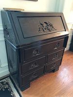 Photo of dark wood Asian-themed secretary desk with carved front panel and drawers, showing chips and scratches.