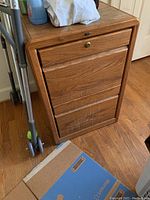 Full view of wooden file cabinet on hardwood floor, showing overall condition and style