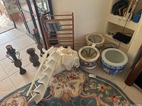 Overview of lot showing candlesticks, porcelain planters, stair shelf, CD rack, tablecloths, and vase on floor with visible tags