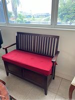 Front view of dark wood storage bench with slatted back and red cushion seat