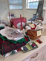 Photo of folded holiday-themed towels, pins, earrings, and a Longaberger basket with hand towels on kitchen counter.