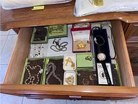 Drawer overview with assorted jewelry pieces laid out in green boxes and plastic bags