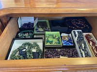 View of drawer containing multiple crystal and turquoise jewelry pieces including necklaces, bracelets, and earrings in various colors such as green, purple, red, blue, white, and amethyst.