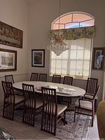 Dining table surrounded by ten mahogany-finish slat-back chairs