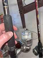 Close-up of fishing rod grip and Shakespeare spinning reel with white fishing line.