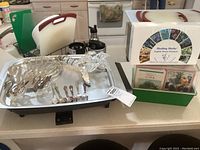 Electric hot plate skillet with sterling silver flatware and glass flower on top, next to Healing Herbs essence set.