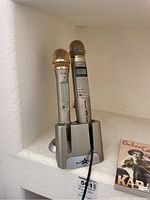 Two Music Star microphones ST-103 and ST-301 in a charging base, with plugged-in cable.