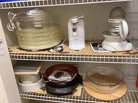 Photo of top and bottom shelves showing Nesco Food Dehydrator, Black & Decker Can Opener, Cuisinart Tea Steeper, Nuwave Hot Plate, and other kitchen items including cutting board and glass bowl.