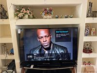 60-inch Samsung TV displaying a music video on screen, set inside a niche with decorative items nearby.