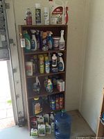 Wooden shelving unit filled with cleaning and pest control supplies, viewed front