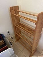 Wooden 4-level shoe rack showing four horizontal bars and solid wood sides.