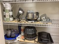 Two wire shelves filled with kitchen items including mixer, bowls, baking pans, blender, teapot, and tea gift collection.