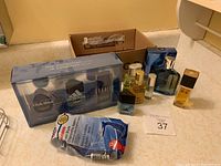 Overview photo of the lot showing colognes and razors with box in background.