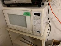 Closed view of the Samsung microwave on white shelf with visible dirt and grime