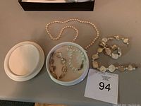 Pearl and shell necklaces along with pearl bracelet and shell earrings displayed on white trays