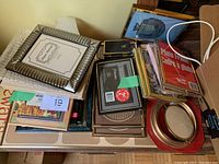 Photo showing assorted photo frames stacked and two new photo albums underneath