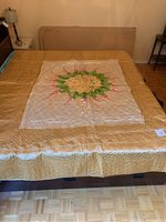 Full bed view of queen size quilt showing the floral center and gold borders spread on bed
