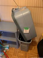 Two gray Rubbermaid bins with the hinged lid open and resting on one bin.