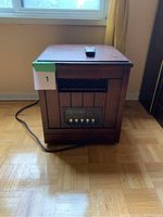 Wood finish side table with built-in heater and control buttons on front, positioned in front of window.