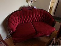 Front view of loveseat showing tufted back, carved wood crest, two seat cushions